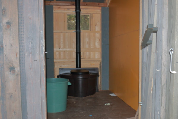 Kuivakäymälä on ovelta katsottuna takaseinällä suoraa ovea vastapäätä. Vasemmalla ennen pönttöä on iso kuivikesaavi. Pöntön takana on ikkuna katonrajassa.